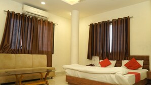 Un dormitorio con cama, sofá, una mesita de centro de cristal y cortinas.