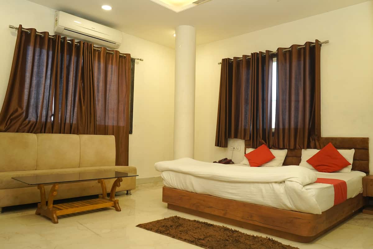 Un dormitorio con cama, sofá, una mesita de centro de cristal y cortinas.