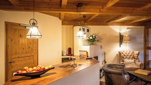 A kitchen with a wooden countertop, a sink, and a bowl of fruit. There is a chair and a table with a board game. - Landhaus & Lodges by Bollants (Bad Sobernheim)