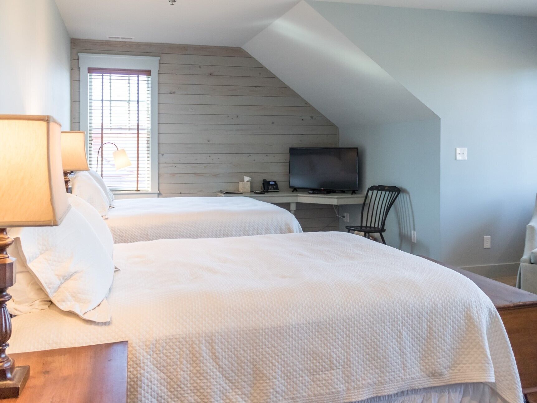 Une chambre avec deux lits, une télévision et un bureau.