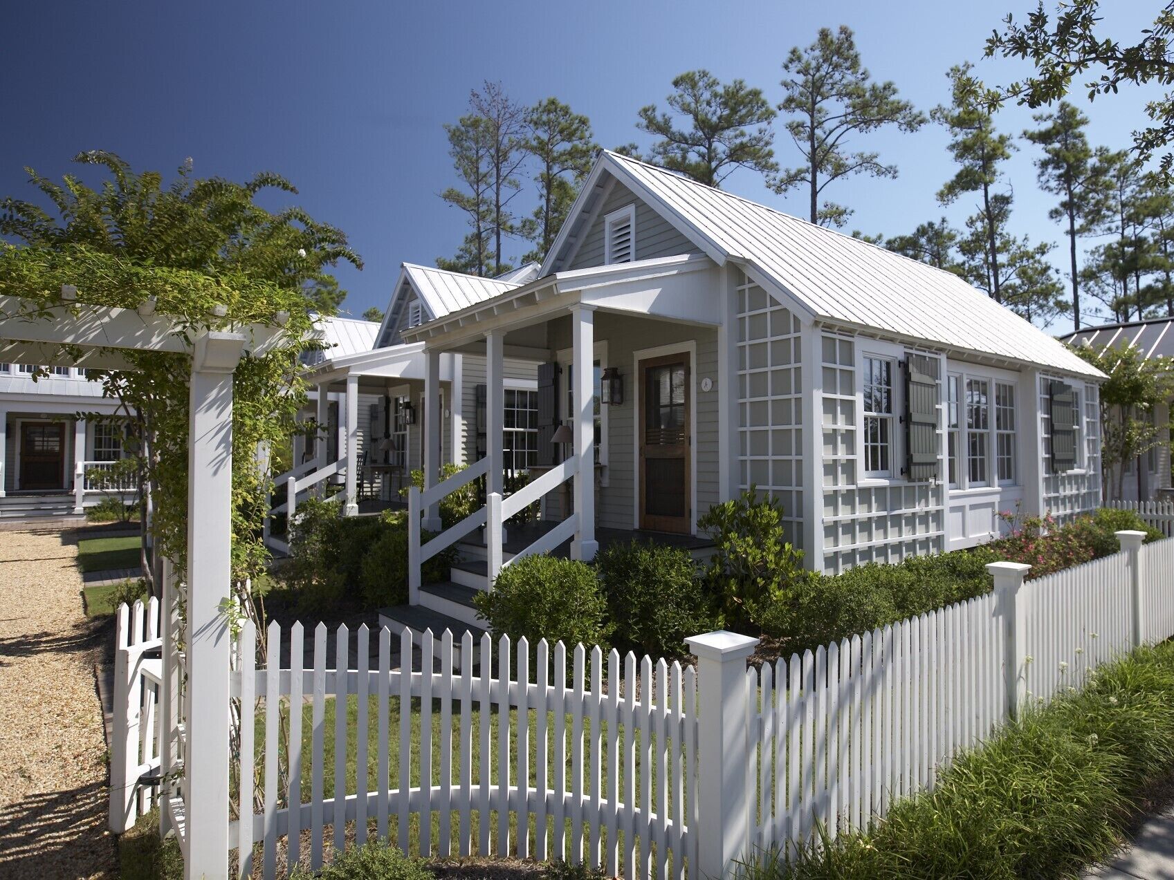 A white colonial-style house with a porch, a picket fence, and a well-maintained lawn.