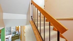 Una escalera con barandillas de madera y peldaños alfombrados que conduce a un piso superior.
