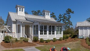 A white house with a covered porch, a wooden deck, and two kayaks on the grass. - Grand Banks Cottage w/Full Kitchen - River Dunes (Oriental)