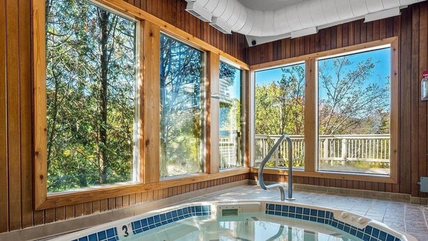 A hot tub with a view of trees through large windows. - Fall Line Condo D6 3 Bedroom Condo (Killington)