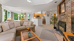 A modern living room with a sectional sofa, a glass coffee table, and a fireplace. - Fall Line Condo D6 3 Bedroom Condo (Killington)