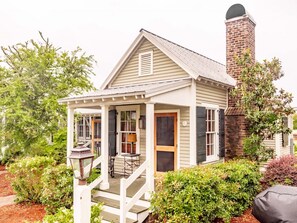A small house with a porch, a chimney, and a garden.