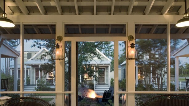 A covered outdoor area with wicker furniture and a fire pit.