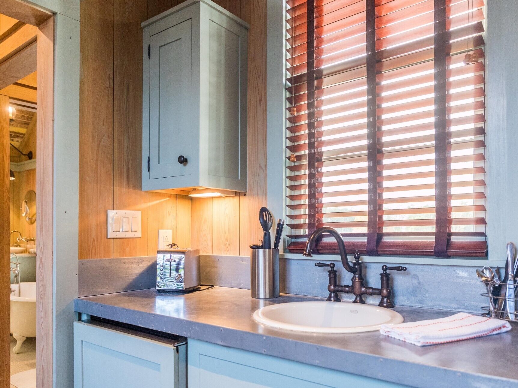 A modern kitchen with a built-in sink, a toaster, and wooden blinds.