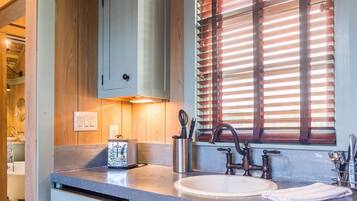 A modern kitchen with a built-in sink, a toaster, and wooden blinds.
