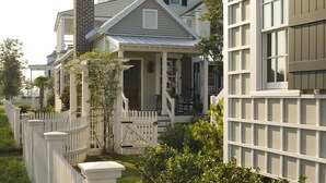 A row of traditional houses with a picket fence, a porch, and a chimney.