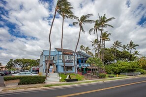 Un bâtiment à deux étages avec une façade bleue, une enseigne indiquant « Mako Jewelry », et des palmiers en arrière-plan.