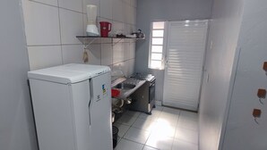 Eine kompakte Küche mit Kühlschrank, Spüle und einem Fenster mit Jalousien.
