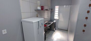 Geladeira, fogão, talheres/pratos/utensílios de cozinha, mesas de jantar