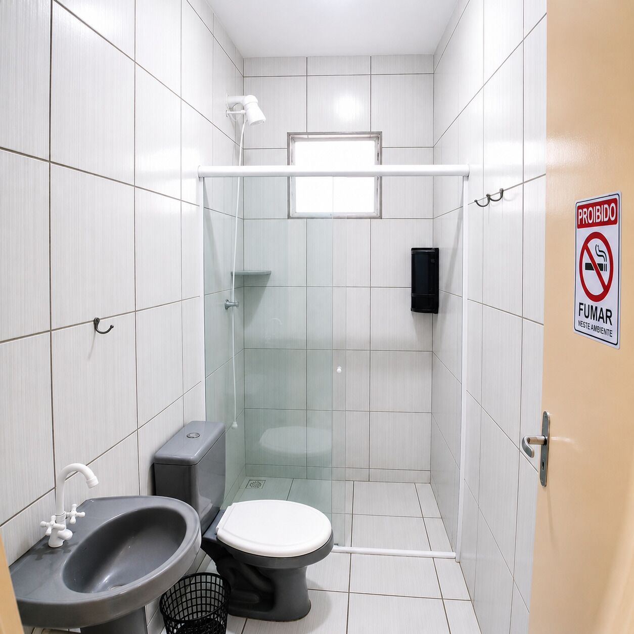 Un baño pequeño con azulejos, que incluye inodoro, lavamanos y cabina de ducha.