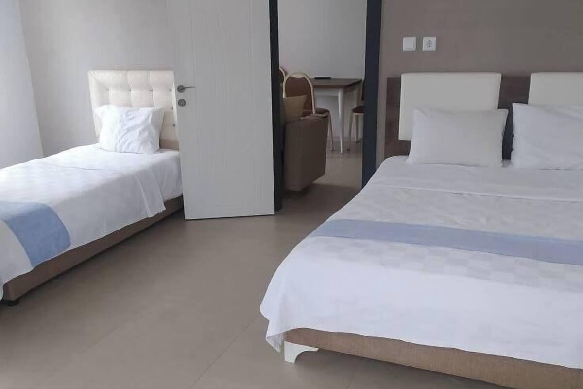A hotel room with two beds, a desk, and a chair.