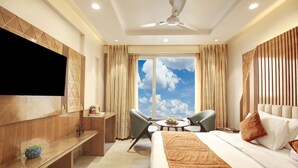 Hotelkamer met een bed, bureau, stoel, televisie en raam met uitzicht op de lucht.