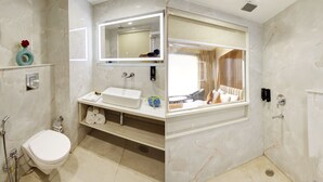 Een badkamer met een wit toilet, een wastafel met een spiegel erboven en een douchehoek.