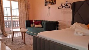 Een moderne slaapkamer met een bed, een bank, een klein tafeltje en uitzicht op het omliggende landschap.