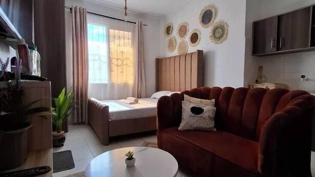 Een moderne woonkamer met een bank, een ronde salontafel, een bed en een plafondventilator.