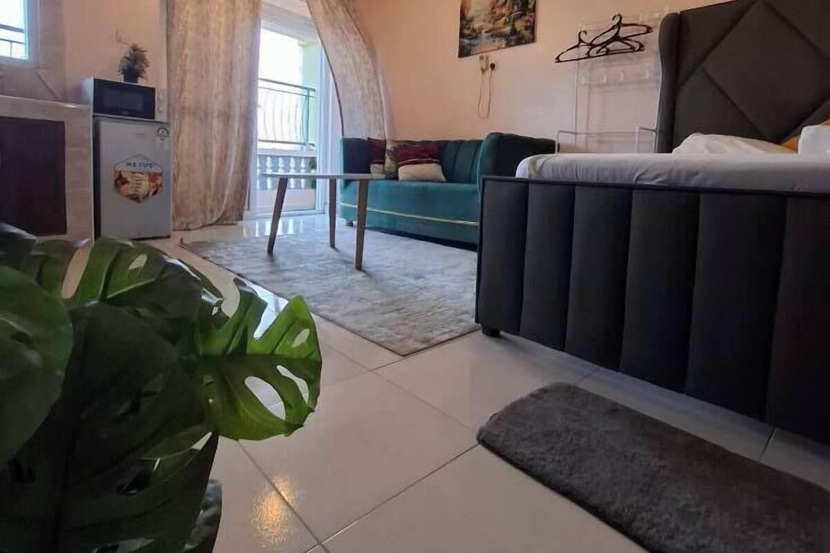 Uma sala de estar moderna com sofá, área de jantar com geladeira e ventilador de teto.