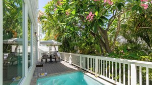 A pool area with a white deck, a table with chairs, and a white fence surrounding the pool.