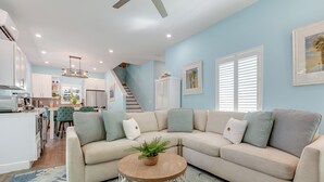 A modern living room with a sectional sofa, a coffee table, and a staircase leading to the upper floor.