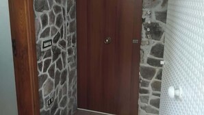 Una entrada de paredes de piedra con una puerta de madera, un letrero y un piso de baldosas.