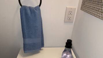 Un bagno con un lavandino bianco, un rubinetto nero e un asciugamano blu appeso a un porta-asciugamani nero, oltre a un dispenser per sapone.