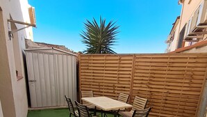 A patio with a table and chairs, surrounded by a wooden fence and a green artificial turf.
