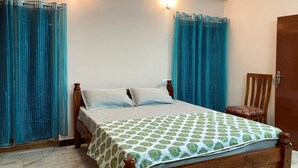 A bedroom with a wooden bed, a chair, and curtains. - GOOD STAY serviced apartments egmore   (Chennai)
