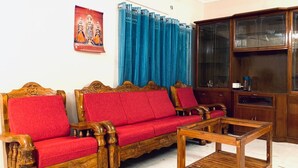 A living room with a wooden sofa set, a wooden coffee table, and a cabinet. - GOOD STAY serviced apartments egmore   (Chennai)