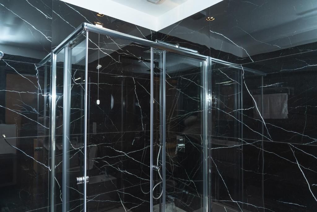 A glass-enclosed shower with a black marble wall.