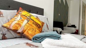 Un lit bien fait, avec une literie à motifs, un coussin décoratif et une serviette pliée.
