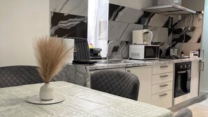Une cuisine moderne équipée d’un four à micro-ondes, d’une cuisinière et d’un four encastrés. Un coin repas avec une table et des chaises est également disponible.