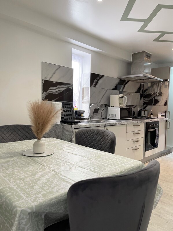 Una cocina moderna con microondas, estufa y horno integrados. Cuenta con un comedor con mesa y sillas.