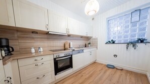 A modern kitchen with white cabinets, a wooden countertop, a built-in oven, and a window with a view.