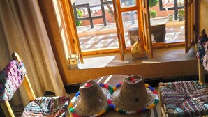 A room with a large window overlooking a landscape, two woven chairs, and a small table with hats. - Villa Calm, Panoramic View of the Lake and Mountains, Ouarzazate Center (Ouarzazate)