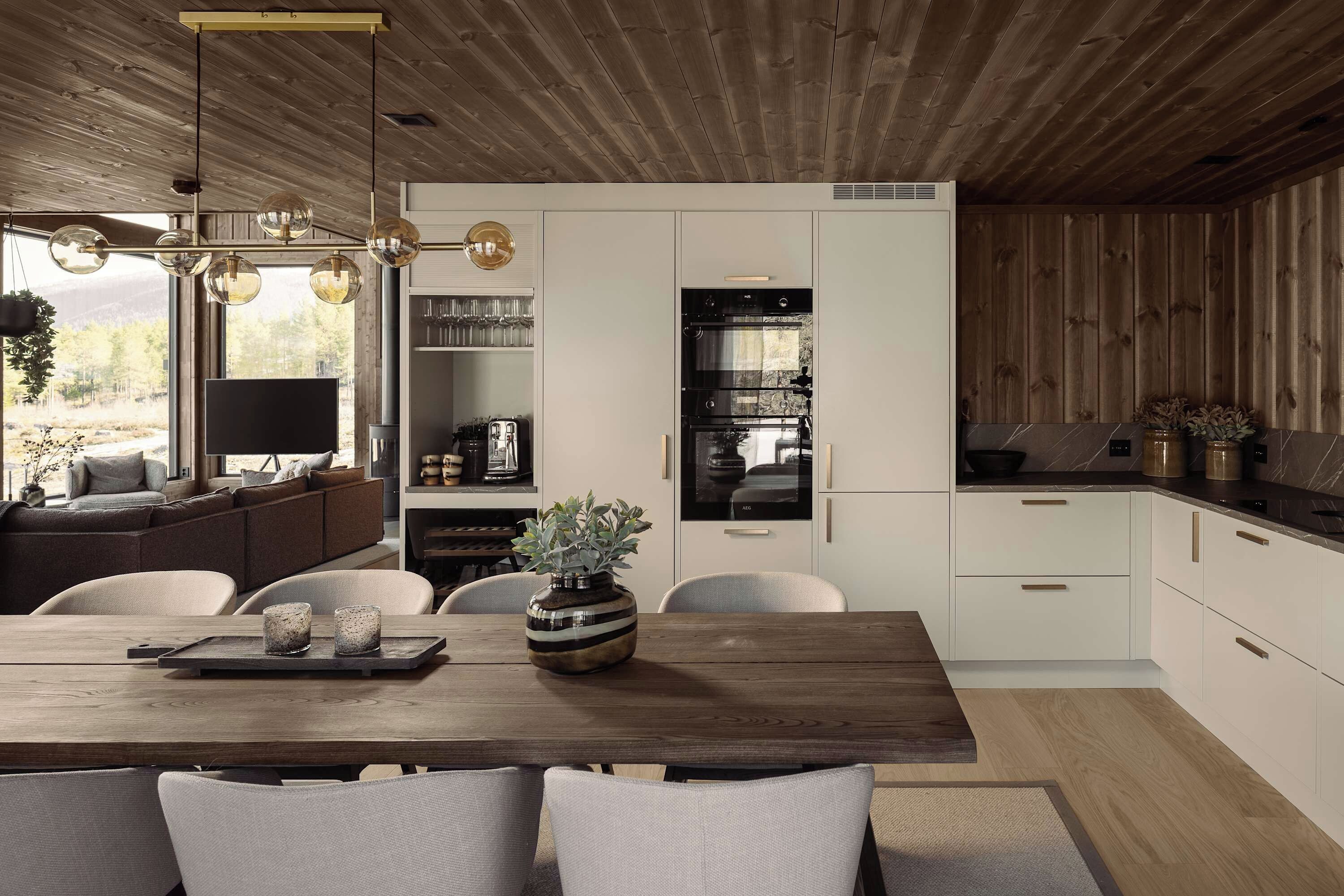 Une cuisine moderne avec des meubles blancs, un four encastré et un coin repas comprenant une table et des chaises en bois.