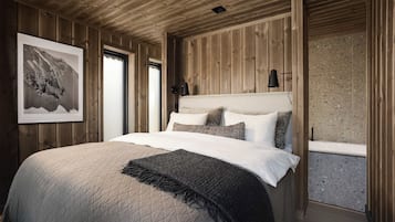Un dormitorio con paneles de madera, una cama, almohadas, un plaid y un cuadro en la pared.