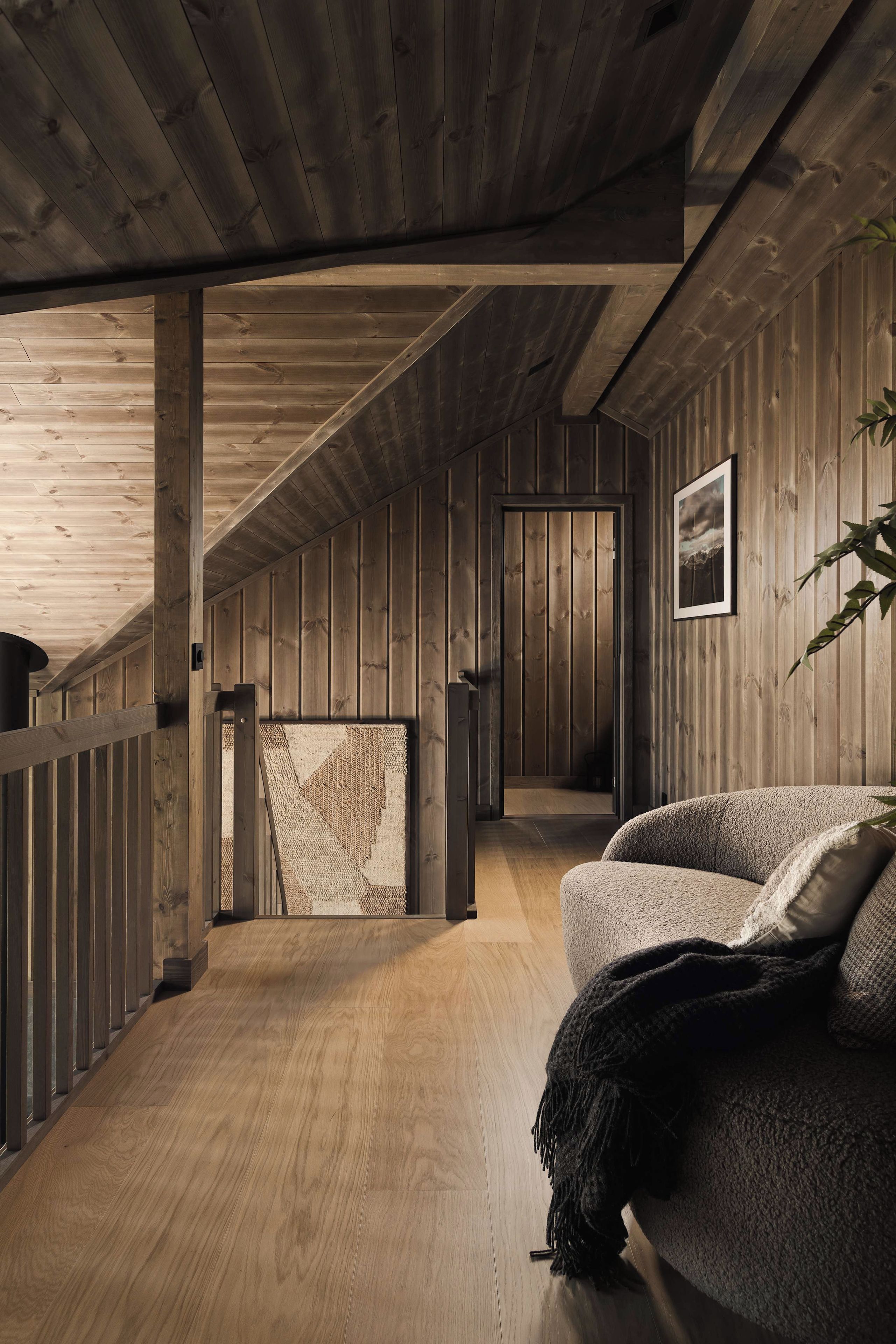 Een houten interieur met een schuine kap, een bank en een ingelijste foto aan de muur.