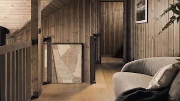 Een houten interieur met een schuine kap, een bank en een ingelijste foto aan de muur.