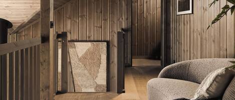 Un interior de madera con techo inclinado, un sofá y un cuadro en la pared.
