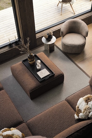Una sala de estar moderna con un sofá modular, un sillón redondo, una mesita auxiliar y una bandeja con objetos decorativos.