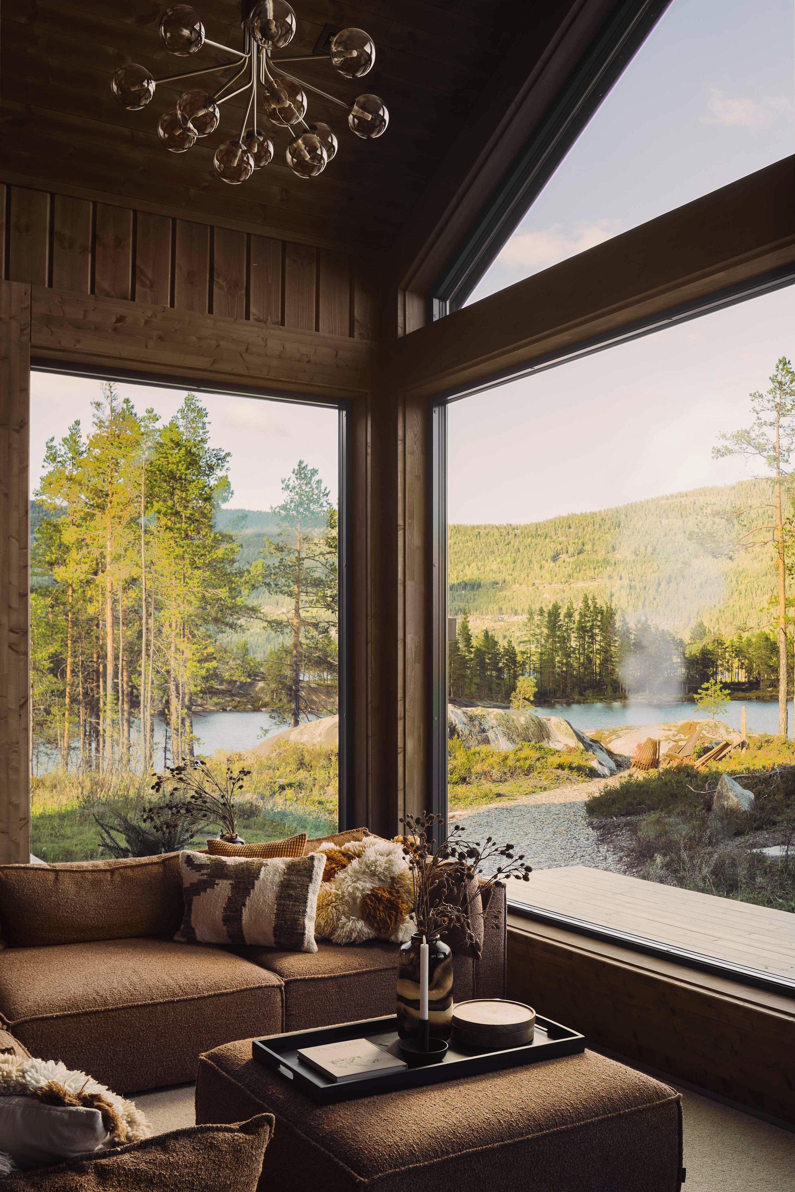 A room with a large window overlooking a forested landscape and a lake.