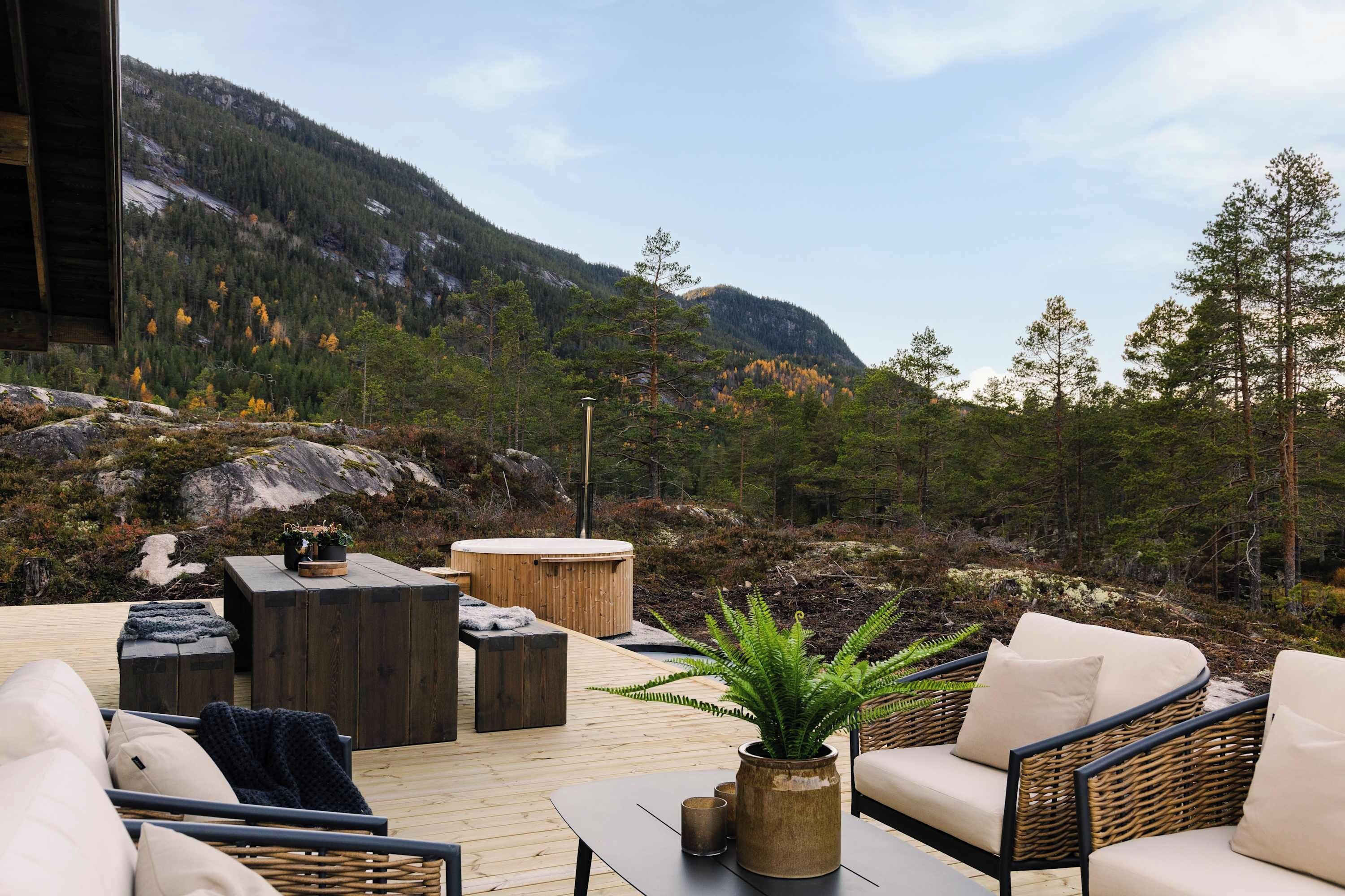 Un espace extérieur aménagé avec des meubles en bois, un jacuzzi et une vue sur un paysage montagneux.