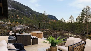 Un espace extérieur aménagé avec des meubles en bois, un jacuzzi et une vue sur un paysage montagneux.