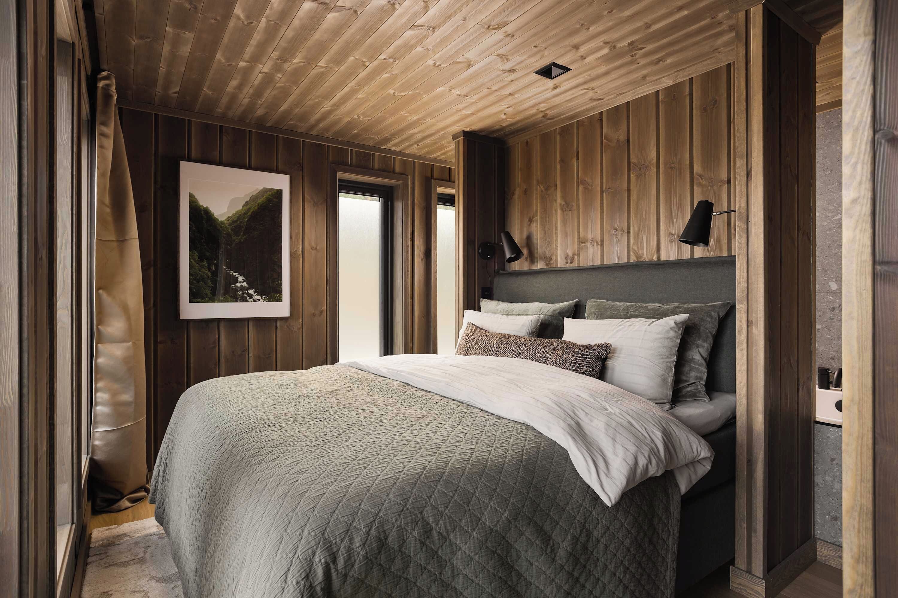 A bedroom with a large bed, a headboard, and a framed picture on the wall.