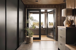 A modern interior with a sliding glass door leading to a balcony, a potted plant, and a wooden cabinet with a lamp.