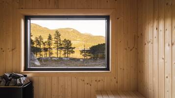 Een chaletinterieur met een groot raam met uitzicht op een bebost landschap.