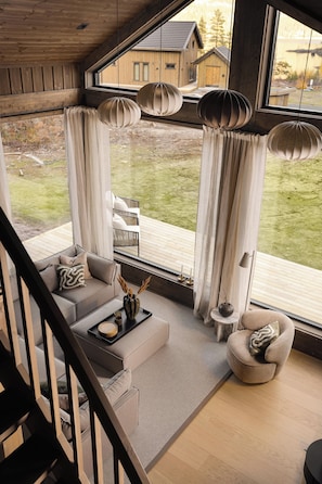A modern living room with a sofa, coffee table, and decorative items. A staircase leads to an upper level.